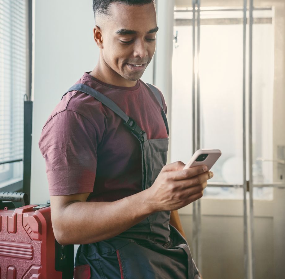 An electrician in a customer’s home, smiling at his phone